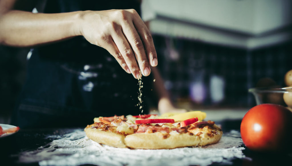 Close up of woman hand putting oregano over tomato and mozzarell