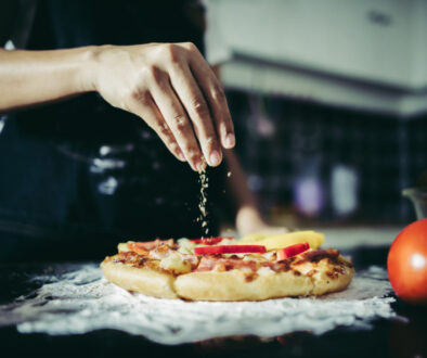 Close up of woman hand putting oregano over tomato and mozzarell