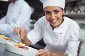 Portrait of female chef garnishing food in kitchen at restaurant